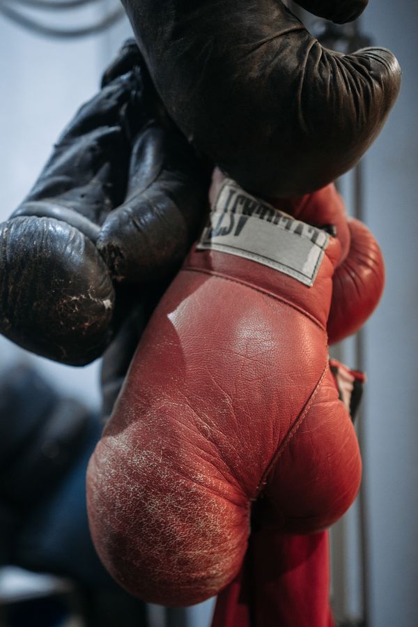 A worn pair of boxing gloves hanging in a gym