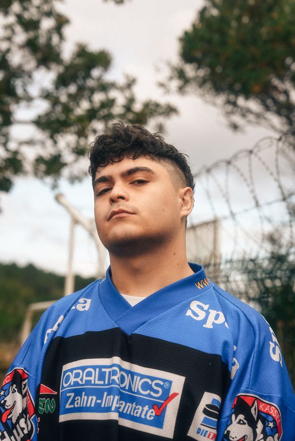 A young man wearing a blue sports jersey outdoors